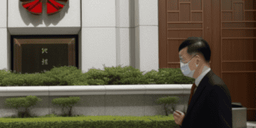 A man wearing a face mask walks past a building in China.