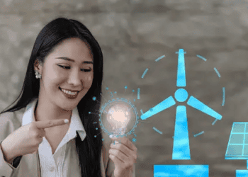 Woman pointing to a glowing lightbulb, representing clean energy solutions like wind and solar power. - Supply Chain News