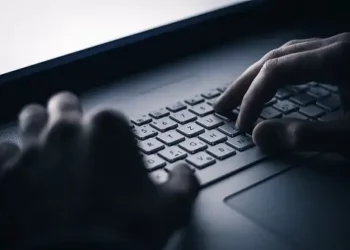 Close-up of hands typing on a laptop keyboard; potential online scam targeting elderly. - Supply Chain News