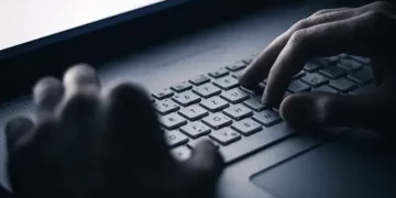 Close-up of hands typing on a laptop keyboard; potential online scam targeting elderly. - Supply Chain News