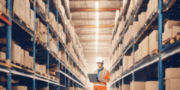 An AI-enhanced worker in a warehouse holding a tablet, enhancing inventory management efficiency.