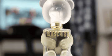 Exploring the future with a Moschino perfume bottle adorned with a cute teddy bear on top.