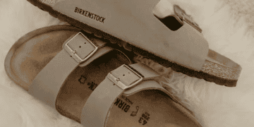 Two pairs of taupe Birkenstock sandals on a fluffy white rug. Birkenstock. - Supply Chain News