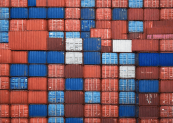 A close up of stacked shipping containers impacted by U.S. tariffs.