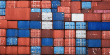 A close up of stacked shipping containers impacted by U.S. tariffs.