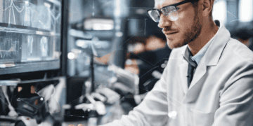 A man in a lab coat working on an advanced technologies computer, deeply focused on understanding the potential impact.