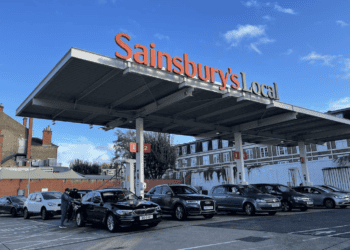 A group of cars parked conveniently under a canopy.