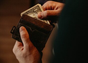 Close-up of hands holding a brown leather wallet and a one dollar bill. - Supply Chain News