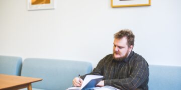 Man reviewing documents at a table, researching export controls on germanium and gallium. - Supply Chain News