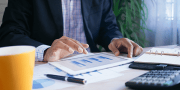 Businessperson reviewing financial data on tablet, charts and calculator nearby. Taiwan luxury goods market analysis. - Supply Chain News