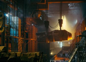 Molten metal being transported in a steel mill. High-temperature industrial process. - Supply Chain News