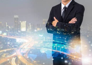 Confident businessman with arms crossed, superimposed over a global network and cityscape, illustrating fintech's impact on global trade. - Supply Chain News