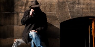 Man in hat sits on a stepladder, appearing suspicious. FBI warning about peer-to-peer payment scams. - Supply Chain News