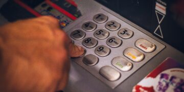 Close-up of a hand entering a PIN at an ATM keypad. Numbers 1-9 are visible. - Supply Chain News