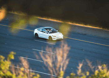 White Tesla Model 3 driving on highway. - Supply Chain News