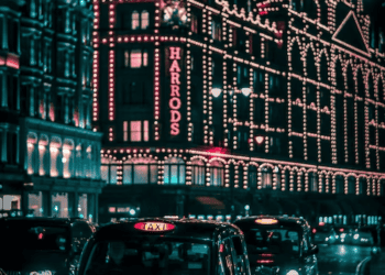 Night view of Harrods department store in London, illuminated with Christmas lights. Black cabs are parked in front. - Supply Chain News