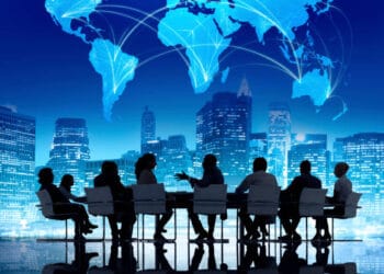 Business people from Bangladesh sitting around a table with a comprehensive overview of global development displayed on a world map.