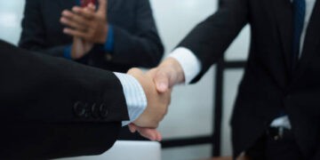 Businesspeople shaking hands, signifying a China-South Korea free trade agreement. - Supply Chain News
