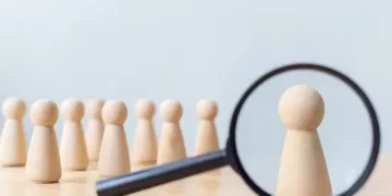 A Privacy-Centric Landscape with a magnifying glass over a group of wooden figures.