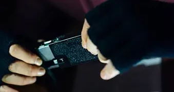 Masked person examining a device, data privacy concerns. - Supply Chain News