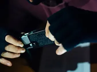 Masked person examining a device, data privacy concerns. - Supply Chain News