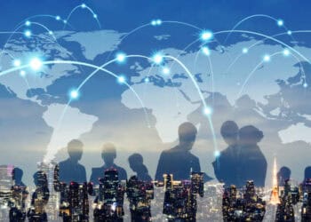 Silhouettes of business people standing in front of a world map, representing the benefits and challenges of economic integration depicted through a global trade report.
