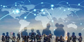 Silhouettes of business people standing in front of a world map, representing the benefits and challenges of economic integration depicted through a global trade report.