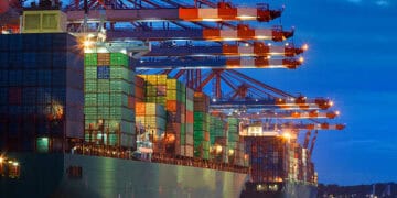 A large container ship docked at night, symbolizing the resilience of global trade despite the ongoing pandemic.