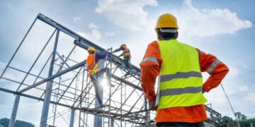 Construction workers on scaffolding assembling a metal framework. - Supply Chain News