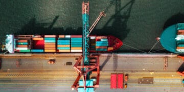 Aerial view of cargo ships and a crane at a port, illustrating increased US coal exports to Europe due to EU sanctions on Russian coal. - Supply Chain News