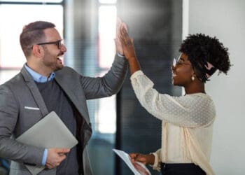Two business colleagues give each other a high five, celebrating success. - Supply Chain News