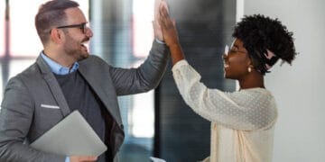 Two business colleagues give each other a high five, celebrating success. - Supply Chain News