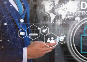 Businessperson using smartphone, data protection icons, and "Data Protection" text overlay. Enhancing fraud risk management. - Supply Chain News