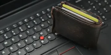 Brown leather wallet with credit cards on laptop keyboard; illustrating online fraud risk. - Supply Chain News