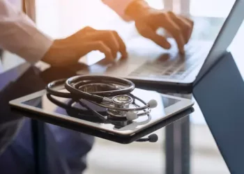 A doctor using a laptop to overcome macroeconomic challenges in the medtech industry while addressing staffing shortages.