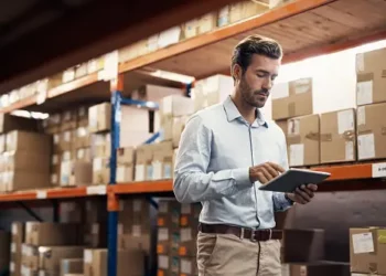 A man using a tablet to revolutionize supplier management in a warehouse.