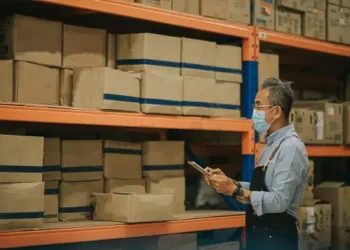 A resilient man wearing a face mask in a supply chain warehouse.