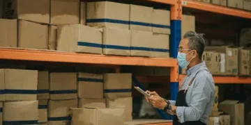 A resilient man wearing a face mask in a supply chain warehouse.