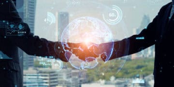 Two businesspeople shaking hands, a digital globe appearing between them, symbolizing international trade and a potential free trade agreement between Israel and Japan. - Supply Chain News