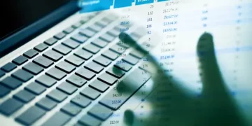 Hands typing on laptop keyboard, MyGov and ATO account data visible on screen. Australian tax fraud. - Supply Chain News
