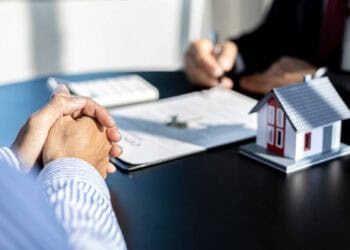 Businesspeople review documents at a table, with a model house present. Economic sanctions impact is discussed. - Supply Chain News