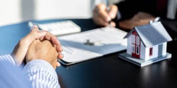 Businesspeople review documents at a table, with a model house present. Economic sanctions impact is discussed. - Supply Chain News