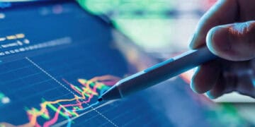 Stylus pointing at financial charts on tablet, illustrating climate-related financial risk management. - Supply Chain News