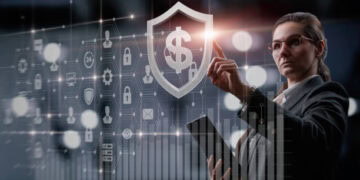 Businesswoman interacts with digital financial security shield displaying a dollar sign, illustrating enhanced KYC measures. - Supply Chain News