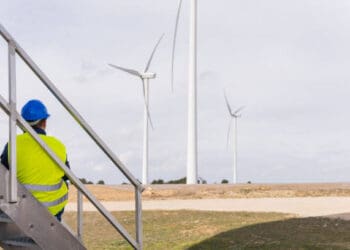 A man utilizing technology to observe wind turbines from a stairway.