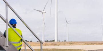 A man utilizing technology to observe wind turbines from a stairway.