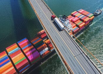 Aerial view of cargo ships and trucks on a bridge, illustrating global trade and economic activity. - Supply Chain News