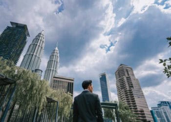 Man in suit looks towards skyscrapers, suggesting economic confidence. - Supply Chain News