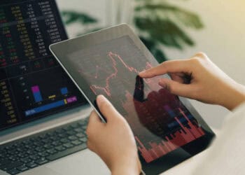 Close-up of hands using a tablet displaying stock market data. India-Russia economic relations. - Supply Chain News