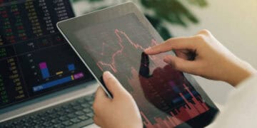 Close-up of hands using a tablet displaying stock market data. India-Russia economic relations. - Supply Chain News